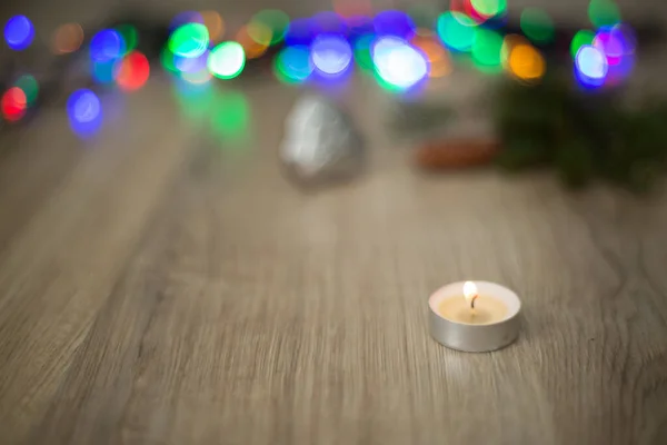 Composizione natalizia della candela su uno sfondo di legno con luce colorata — Foto Stock