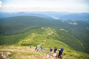 Büyük yeşil bir çayırın üzerinde mavi gökyüzünde beyaz bulutlar. Yüksek yeşil dağ