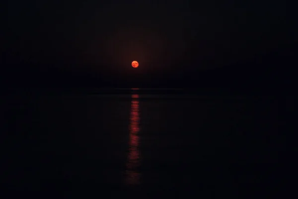 在平静的海面上，漆黑的夜晚，满月在天空中闪烁着光芒 — 图库照片