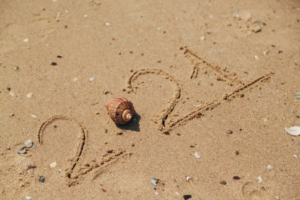 Word 2021 Escrito en la arena de una playa. Año Nuevo 2021 texto en la playa del mar —  Fotos de Stock