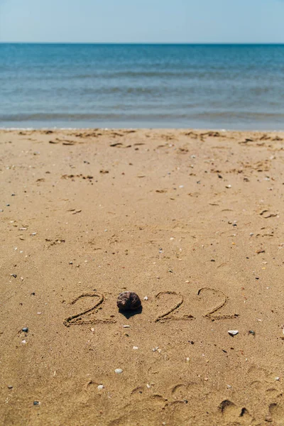 Texto 2022 Escrito en la arena de una playa. El mar sobre un fondo de letras —  Fotos de Stock