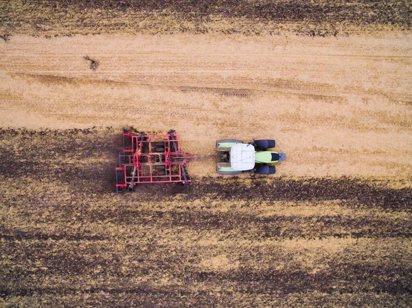 Zbieram plony na polu. Widok z lotu ptaka. Uprawa gruntu z ciągnikiem — Zdjęcie stockowe