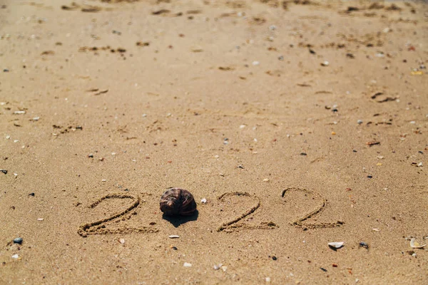 Palabra 2022 Escrito en la arena de una playa. Copiar el espacio pasado. —  Fotos de Stock