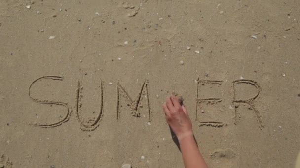 Літо написано на піску пляжу. Море на задньому плані листів — стокове відео