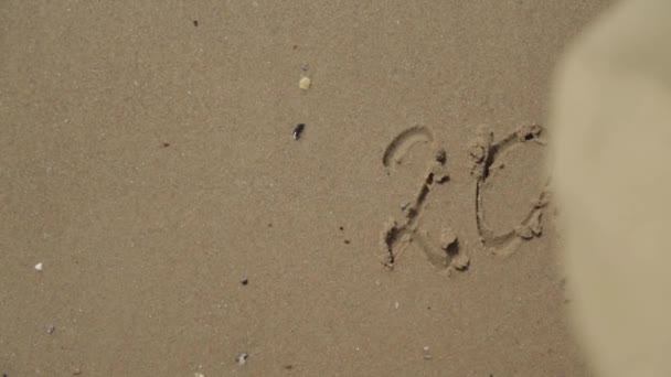 Text 2021 Skrivet på sandstranden. Havet på en bakgrund av bokstäver — Stockvideo