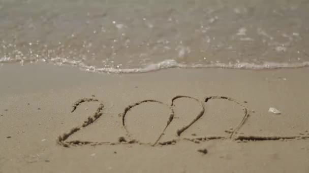 Wort 2022 geschrieben auf dem Sand eines Strandes. Neujahrstext 2022 am Strand des Meeres — Stockvideo
