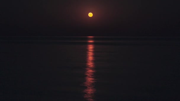 La Luna Roja Llena Brilla Brillantemente en el Cielo en una Noche Oscura Sobre el Mar Calma. Hermoso Timelapse camino de la luna en el agua — Vídeos de Stock