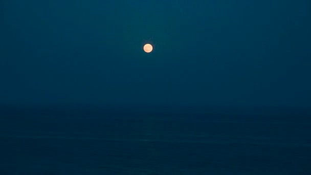 A telihold fényesen ragyog az égen egy sötét éjszakán a nyugodt tenger felett. Gyönyörű Hold út a vízen — Stock videók