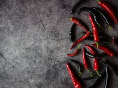 Koyu beton zemin üzerinde kırmızı ve siyah biber kabukları