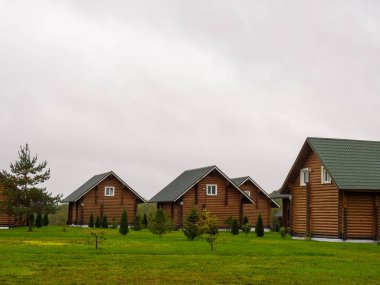 Birbirinin aynısı büyük ahşap evler çimlerle kaplı arka bahçeleri var.
