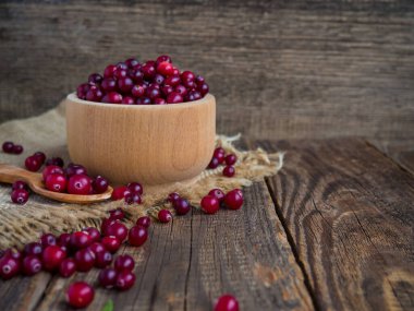 Kırsal bir masadaki ahşap bir kasede taze kızılcıklar..