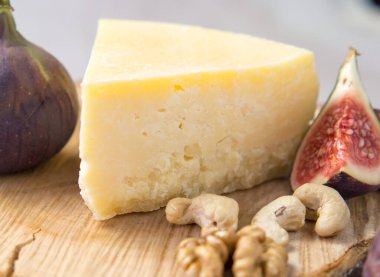 Tahta bir tahtanın üzerinde incir ve fındıklı sert peynir çeşitleri.