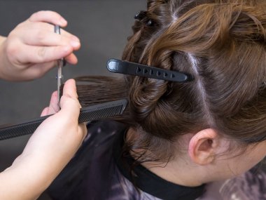 Bir kadının saç kesimine yakın çekim. Berber dükkanındaki güzel, genç esmer kız. Kuaför saçını yapıyor..