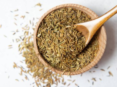 Tahta kaşıkta kimyon ya da kimyon hafif beton arka planda izole edilmiş. Yakın plan.