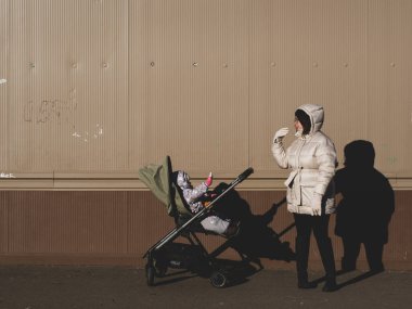 Anne ve çocuk kışın bebek arabasıyla yürür.