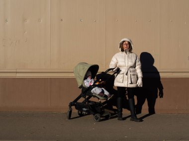 Anne ve çocuk kışın bebek arabasıyla yürür.