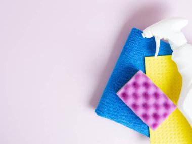 Beyaz şişe, paçavra, mor arka planda sünger mutfak, banyo ve diğer yerlerin çeşitli yüzeylerini temizlemek için bir set. Boşluğu kopyala