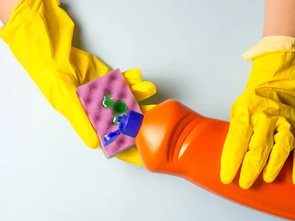 黄色の手袋の女性は食器洗浄ジェルをスポンジに注ぐ 台所の家事 — ストック写真