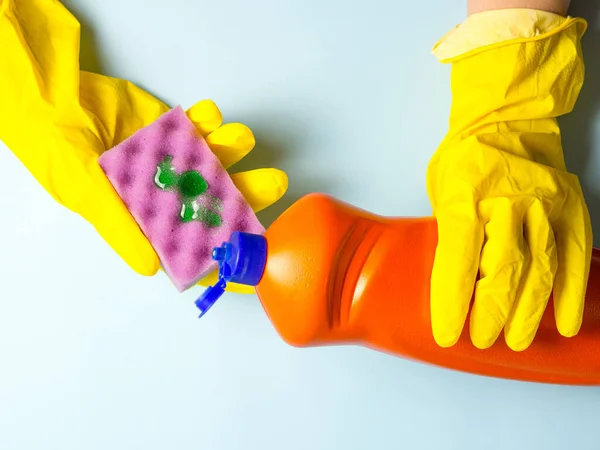 黄色の手袋の女性は食器洗浄ジェルをスポンジに注ぐ 台所の家事 — ストック写真