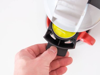 Bir adamın eli kahve makinesine kapsül koyar, kapsül kahve makinesine..