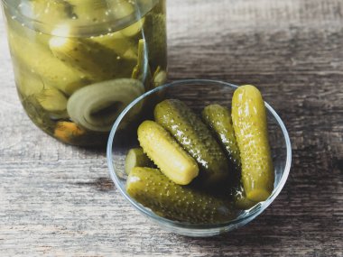 Tahta bir masa ve turşu kavanozunda salatalık turşusu.