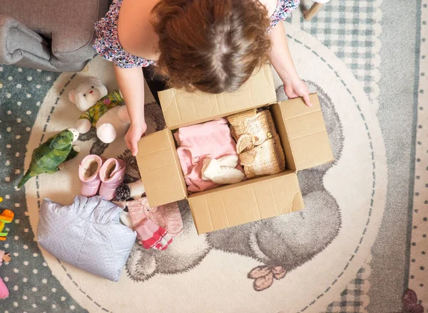 Kışlık bebek kıyafetleri bağış konsepti. Evde eski giysileri hazırlayan kadın..