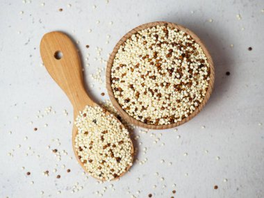 Kase içinde çiğ kinoa ve hafif beton arka planda kepçe. Sağlıklı ve diyet süper yiyecekler.