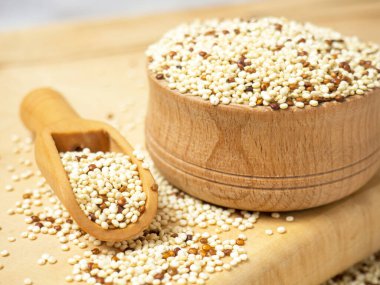 Kase içinde çiğ kinoa ve hafif beton arka planda kepçe. Sağlıklı ve diyet süper yiyecekler.