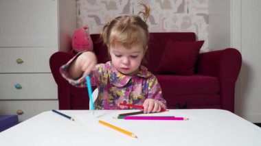 Küçük kız renkli kalemlerle resim yapmayı öğreniyor.