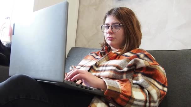 안경을 소녀가 침대에 앉아서 노트북으로 일하고 — 비디오