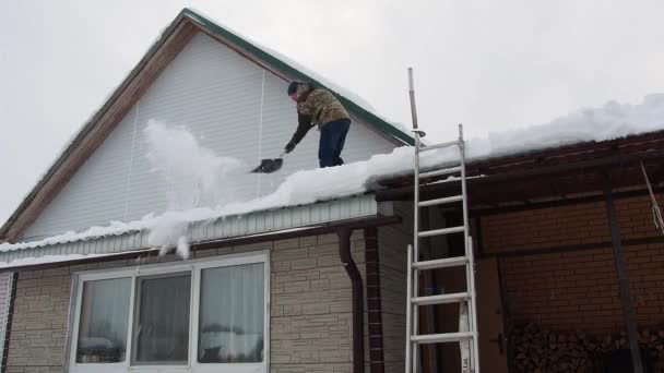 Man Tar Bort Snö Från Taket Ett Helt Snötäckt Hus — Stockvideo