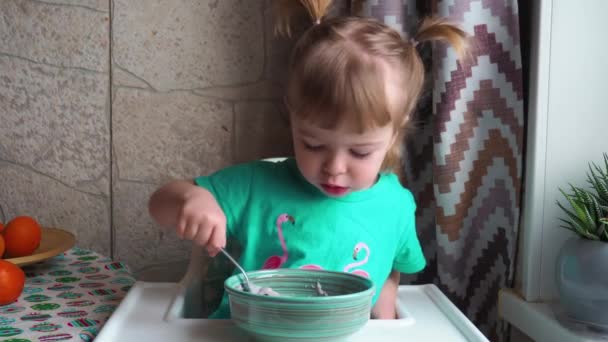 Little Girl Green Dress Sits High Chair Eats Baby Porridge — Stock Video