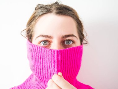 Güzel bir kızın yüzü pembe bir kazağın boğazıyla kaplıydı.