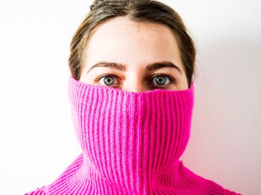 Güzel bir kızın yüzü pembe bir kazağın boğazıyla kaplıydı.