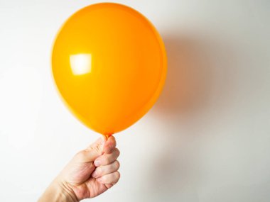 Adamın eli turuncu bir balonu tutuyor.