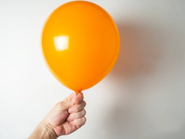 Adamın eli turuncu bir balonu tutuyor.