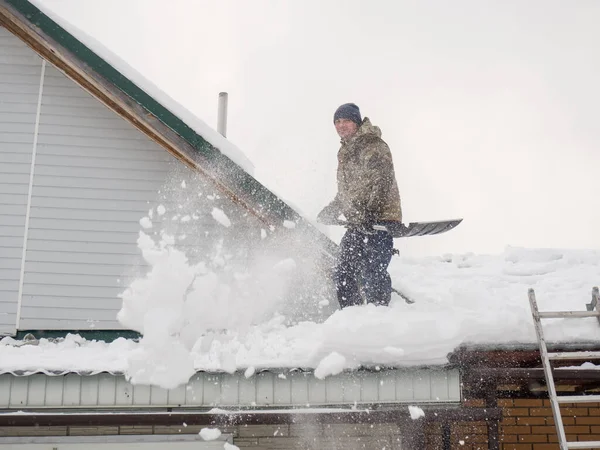 Mężczyzna Usuwa Śnieg Dachu Całkowicie Pokrytego Śniegiem Domu Łopatą Dużo Zdjęcie Stockowe