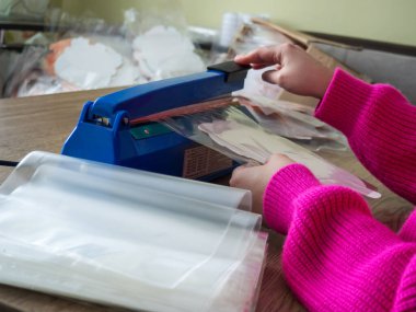 Ev yapımı için el çantası mührü. Bir kız bitmiş ürünleri manuel torbayla paketliyor.