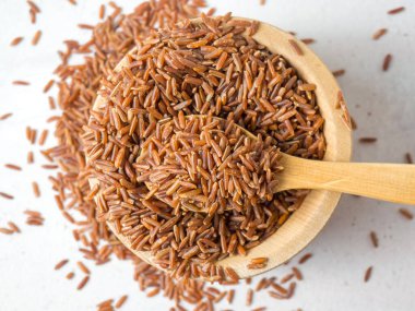 Tahta bir kasede kırmızı pirinç, yere saçılmış kırmızı pirinç. Yaklaş.