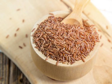 Tahta bir kasede kırmızı pirinç, yere saçılmış kırmızı pirinç. Yaklaş.