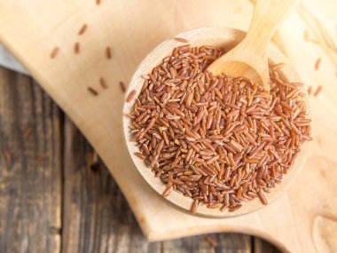 Tahta bir kasede kırmızı pirinç, yere saçılmış kırmızı pirinç. Yaklaş.