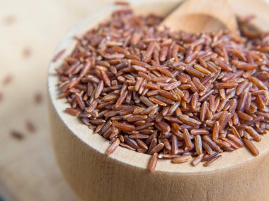 Tahta bir kasede kırmızı pirinç, yere saçılmış kırmızı pirinç. Yaklaş.