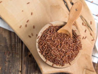 Tahta bir kasede kırmızı pirinç, yere saçılmış kırmızı pirinç. Yaklaş.