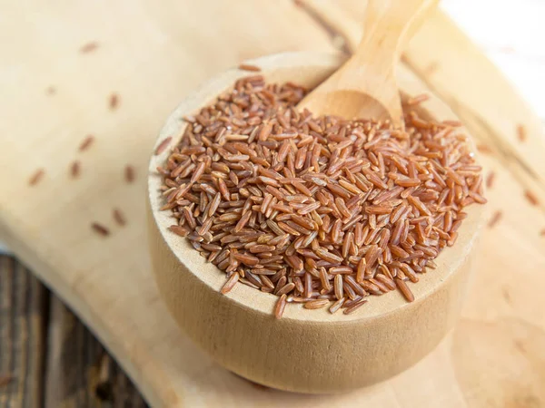 Tahta bir kasede kırmızı pirinç, yere saçılmış kırmızı pirinç. Yaklaş.