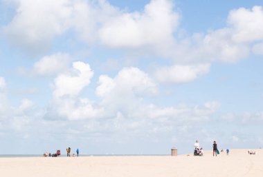 Açık mavi gökyüzü ve denizin üzerinde beyaz dinamik bulutlar, grisont manzarası, kumsalın ince kenarı.