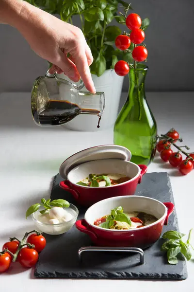 Italian caprese salad, baked cherry tomatoes, mozzarella and basil on a white table, still life — Stock Photo, Image