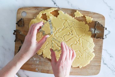 Noel kurabiyeleri için kısaekmek hamurundan figürleri kesme süreci