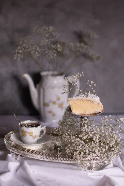 White still life with cheesecake and gypsophila and cup of tea, light and airy — Stock Photo, Image