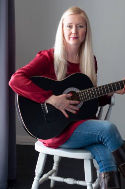 Siyah gitarlı, kırmızı elbiseli güzel sarışın kadın, en sevdiği hobi.