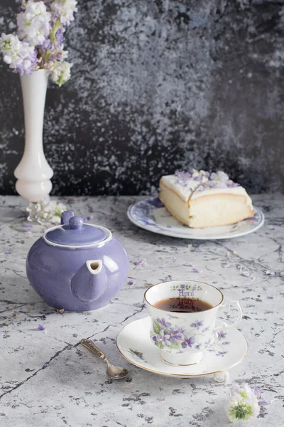 Still life with black tea and cheese cake, spring bouquet,delicate lilac flowers — Stock Photo, Image